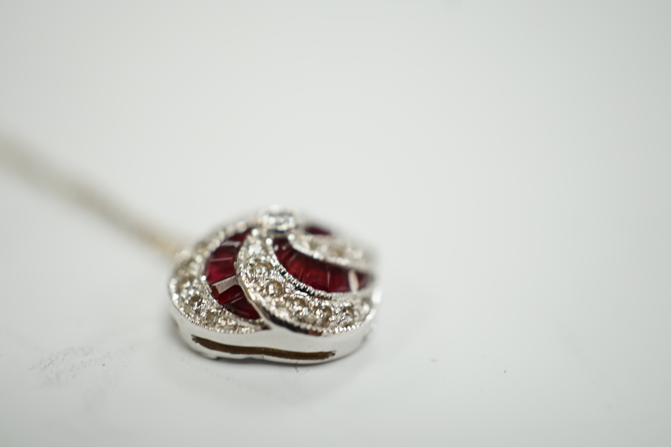 A modern 18ct white gold, ruby and diamond cluster set pendant, 14mm, on a 750 white metal fine link chain, 39cm, gross weight 3.4 grams.
